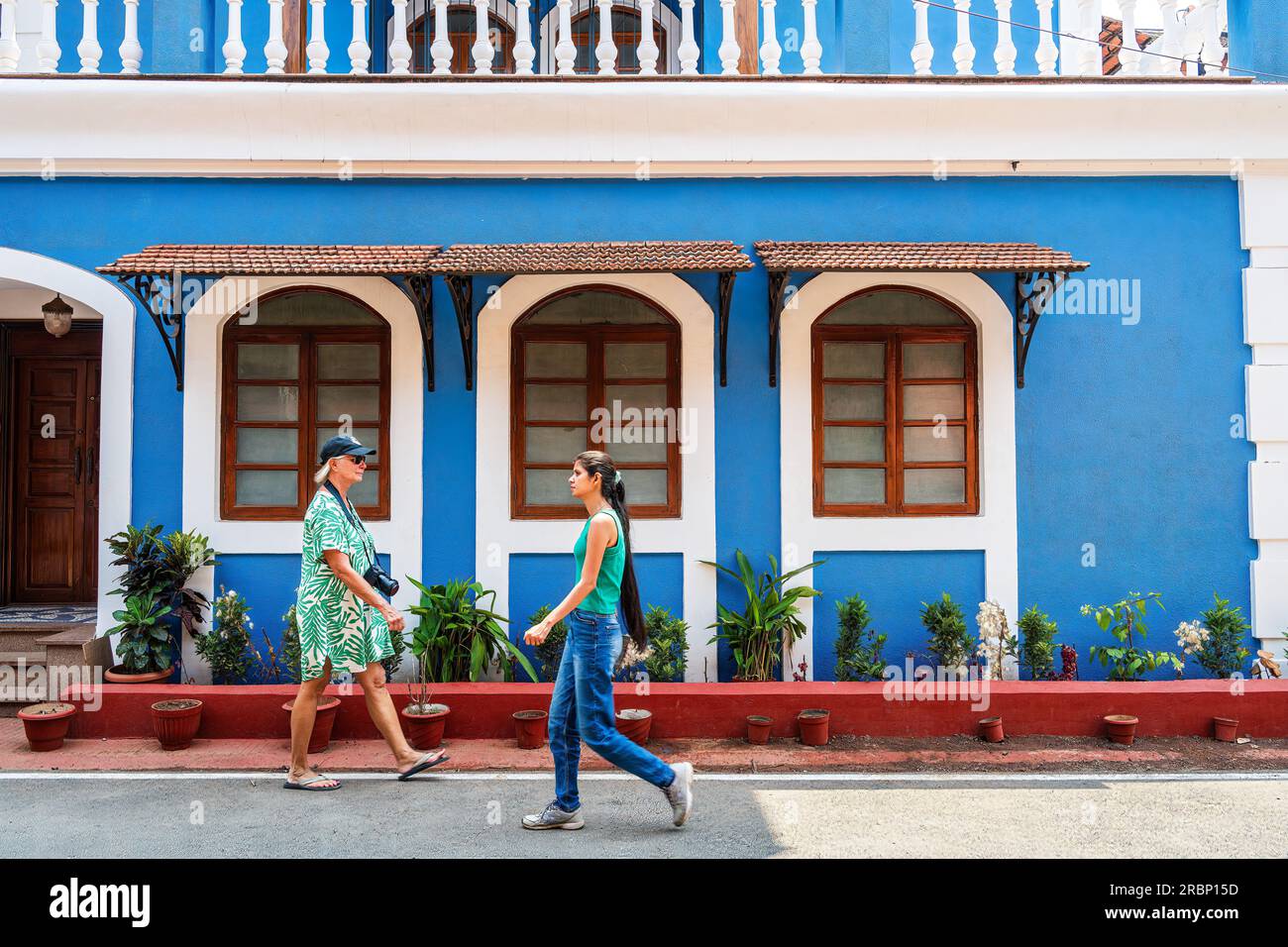 Goa, Indien -- 10. April 2023. Zwei Frauen, eine Tourist, die andere ein Einheimischer, machen einen Spaziergang in einem wohlhabenden Viertel in Goa India. Stockfoto