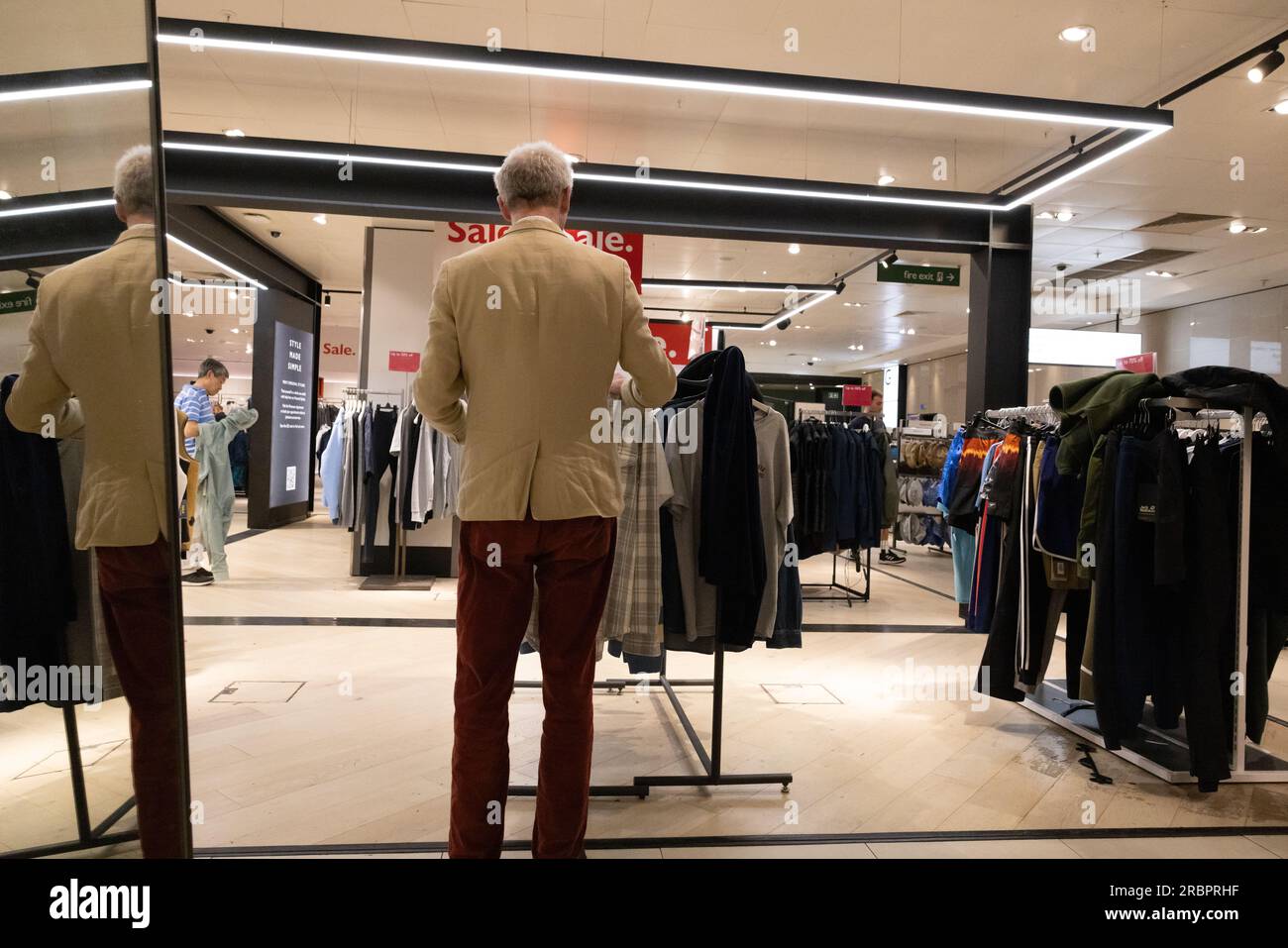 Ein Mann probiert Kleidung in John Lewis, Oxford Street, London, England, Großbritannien Stockfoto