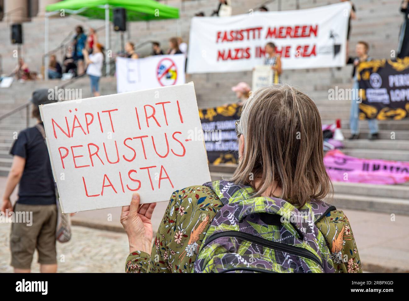 Näpit irti perustuslaista. Demonstranten mit einem Pappschild bei der Demonstration gegen die reiche Regierung vor dem Parlamentsgebäude. Stockfoto