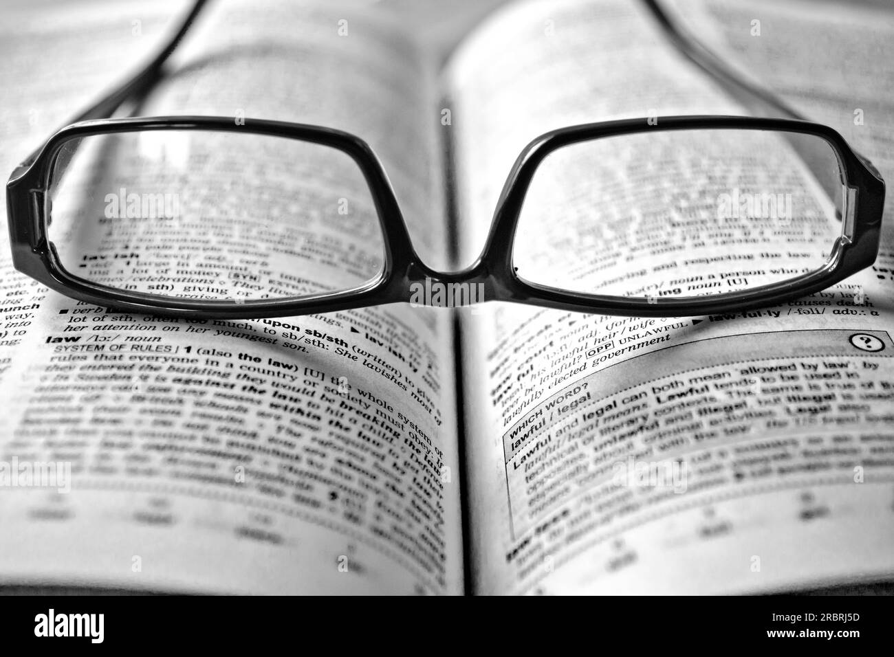 Schwarze Brille liegt auf einem Wörterbuch Stockfoto