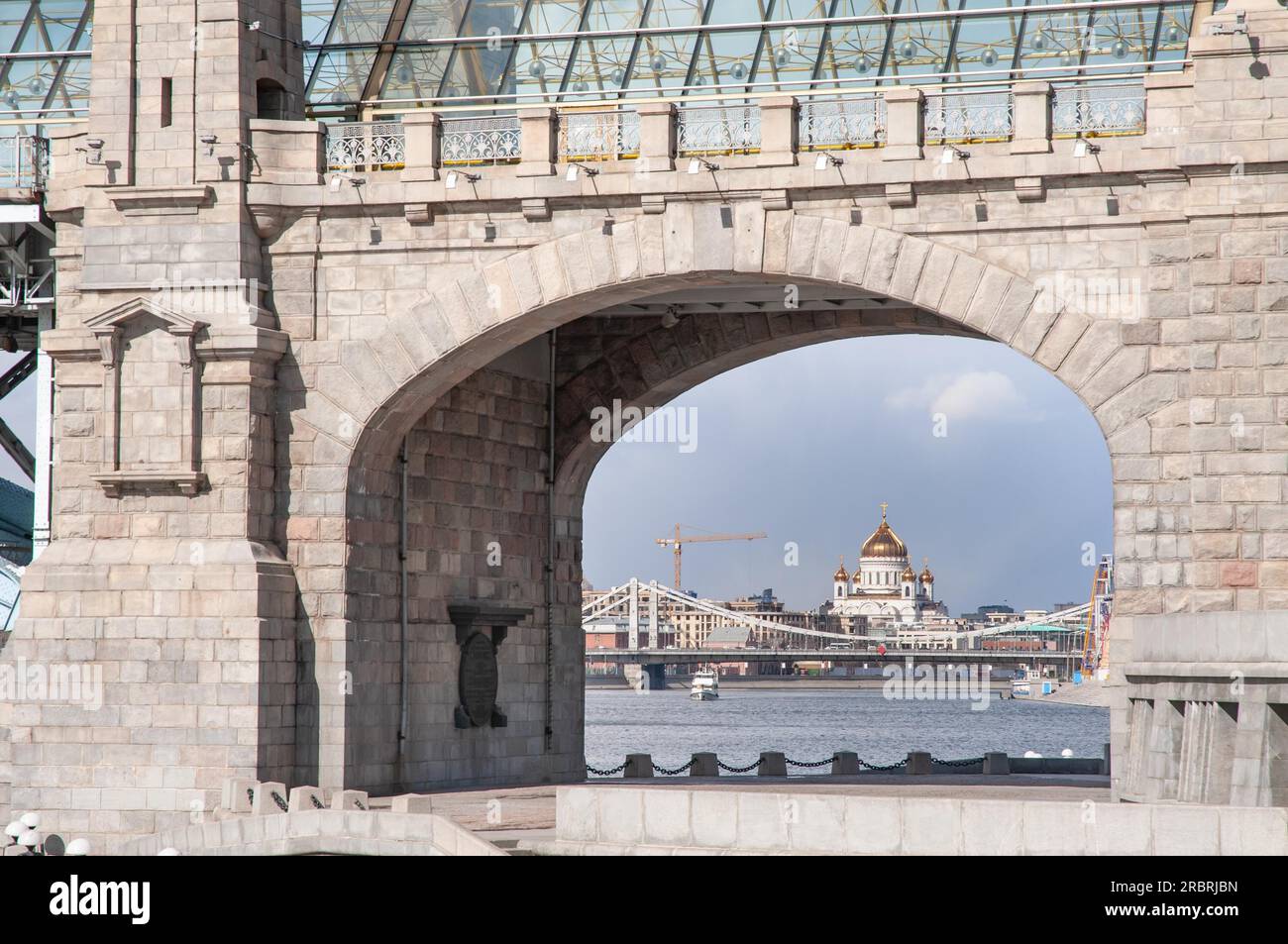 Christuskathedrale, der Erlöser, durch den Hauptbogen der Andreevsky-Eisenbahnbrücke von der Seite des Neskuchny-Gartens in Moskau, Russisch Stockfoto