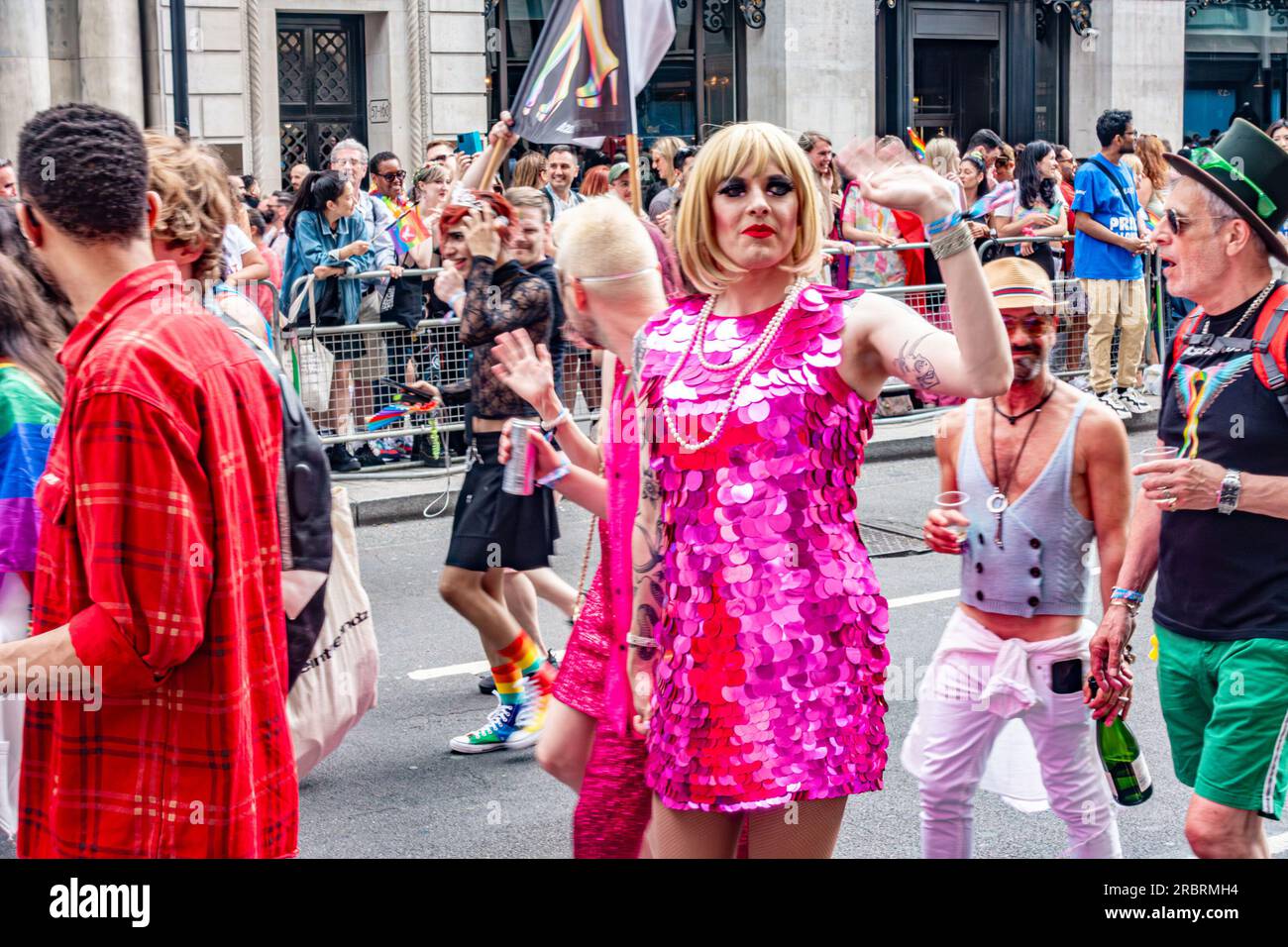 Ein Teilnehmer der alljährlichen London Pride-Veranstaltung am 1. Juli 2023 auf Piccadilly in London trägt ein glitzerndes rosa Kleid und winkt den Massen zu. Stockfoto