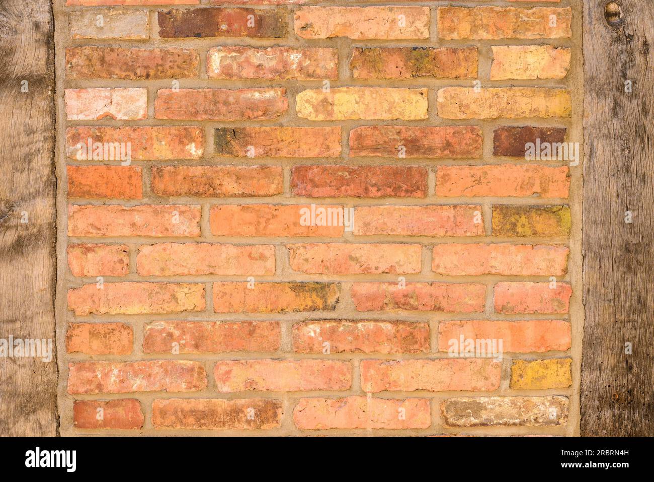 Alte Ziegel Wand Hintergrundtextur mit hölzernen Pfosten auf beiden Seiten des alten dünnes Gesicht Ziegel gebaut Stockfoto