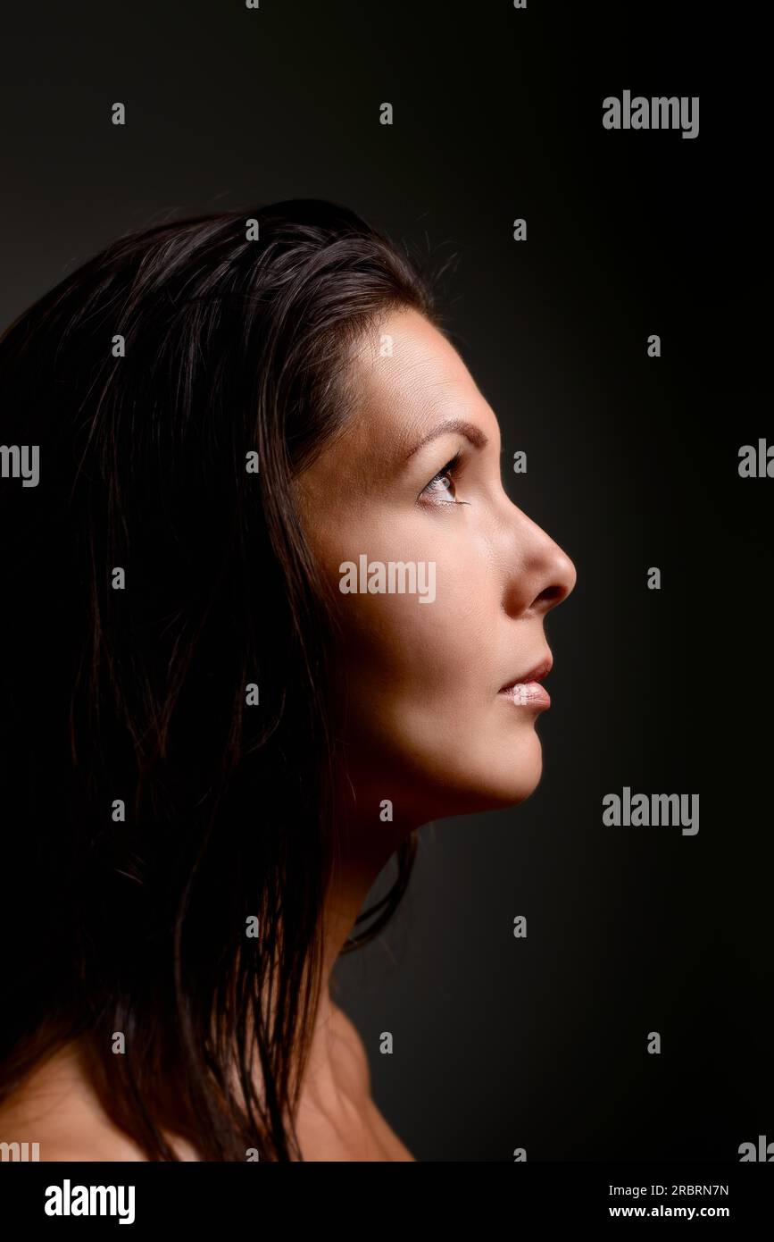 Höhenplan einer schönen schweren ruhige junge Frau stehen im Schatten ins Licht mit einem Blick der Sehnsucht und Einsamkeit starrte Stockfoto