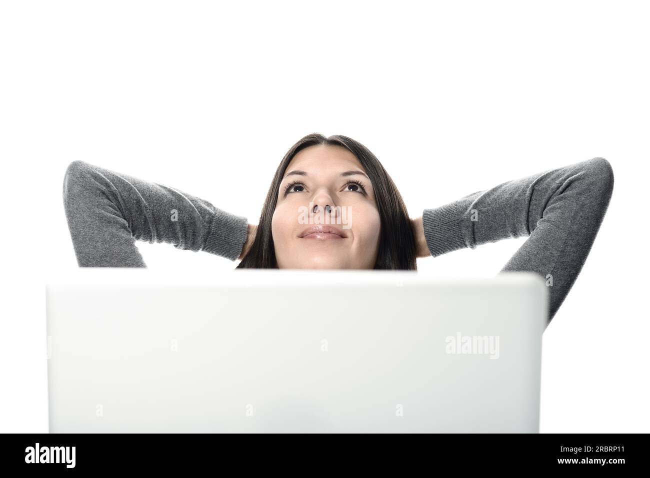 Lächelnde, hübsche Frau, die sich entspannt, mit den Händen am Hinterkopf, während sie nach oben blickt, After Computer Works. Isoliert auf weißem Hintergrund Stockfoto