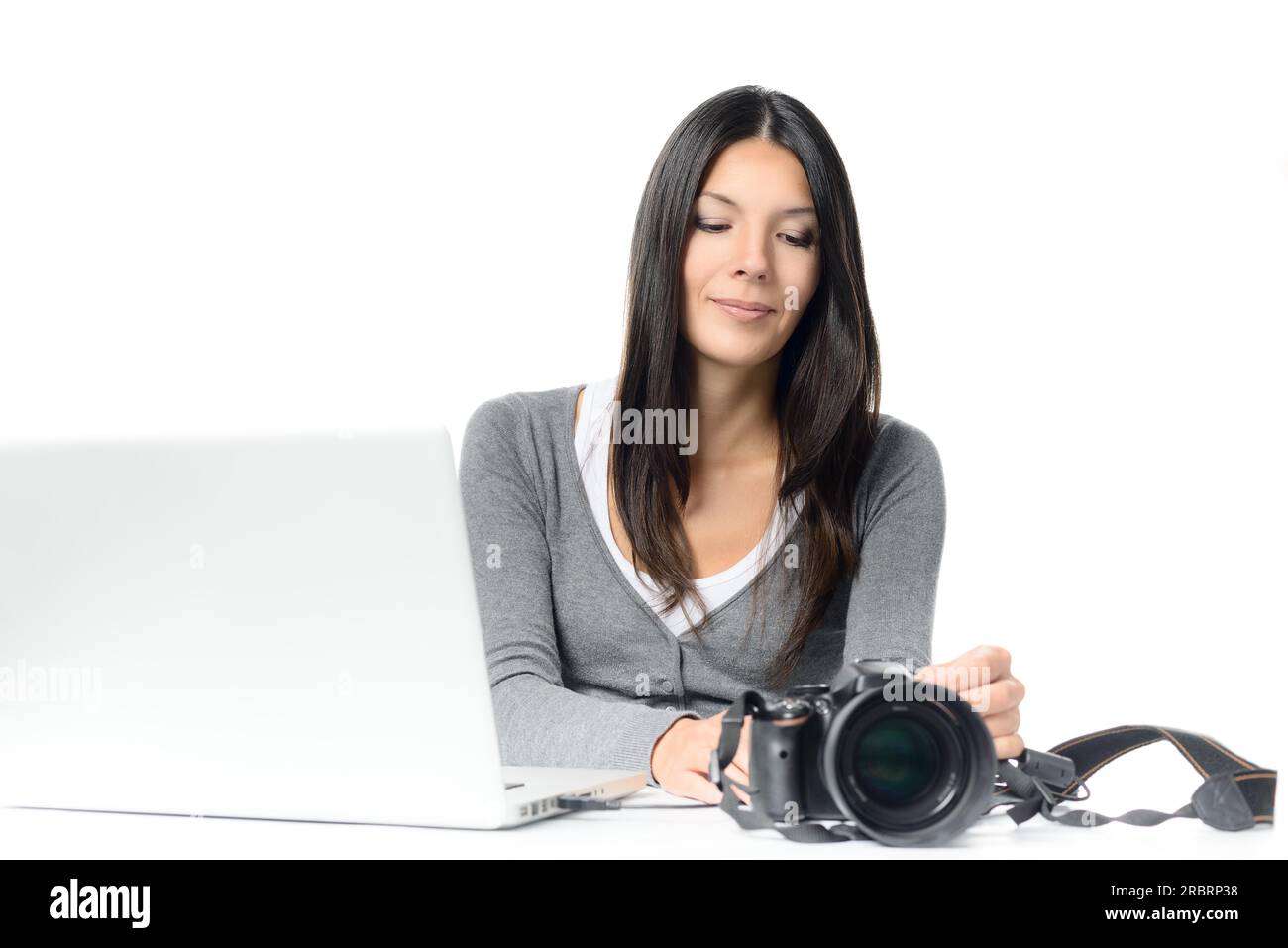 Junge attraktive Frau, die die DSLR-Kamera mit einem Laptop verbindet, um Fotos und Videos zu übertragen, isoliert auf weißem Hintergrund Stockfoto