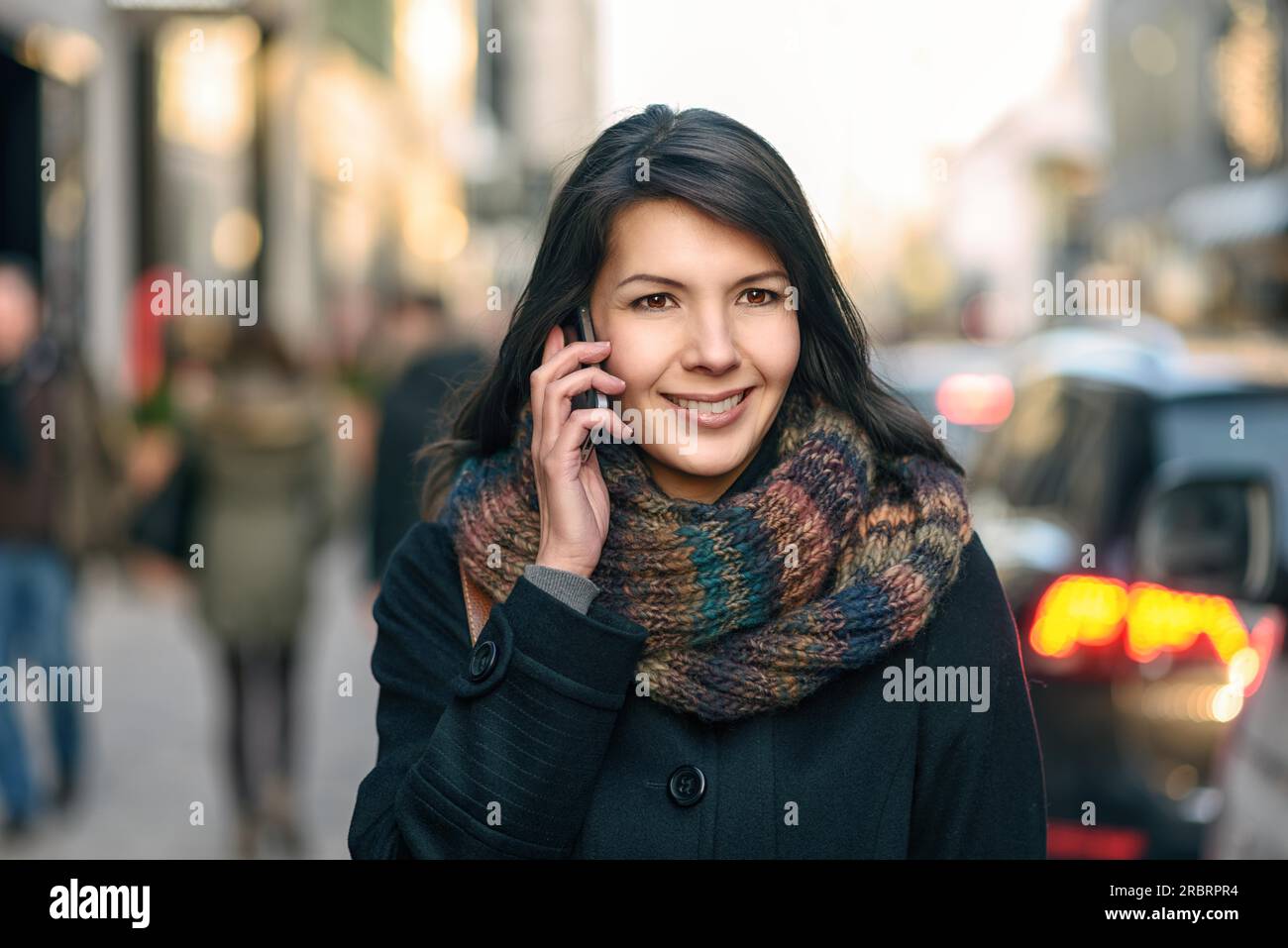 Lächelnde junge Frau im Herbst Mode telefonieren während des Gehens in der Stadt Stockfoto