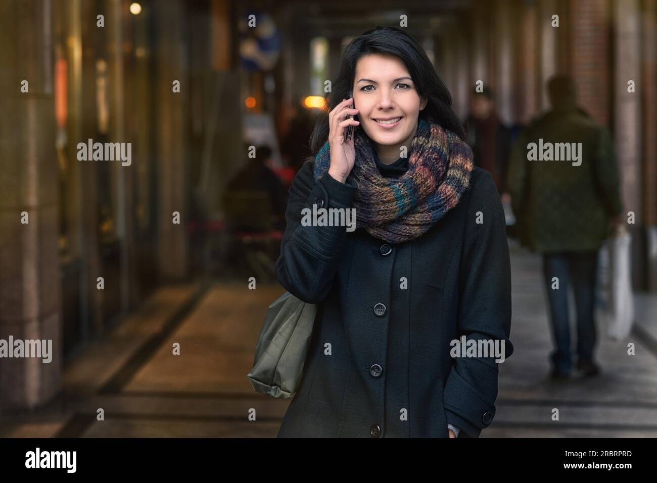 Lächelnde junge Frau im Herbst Mode telefonieren während des Gehens in der Stadt Stockfoto
