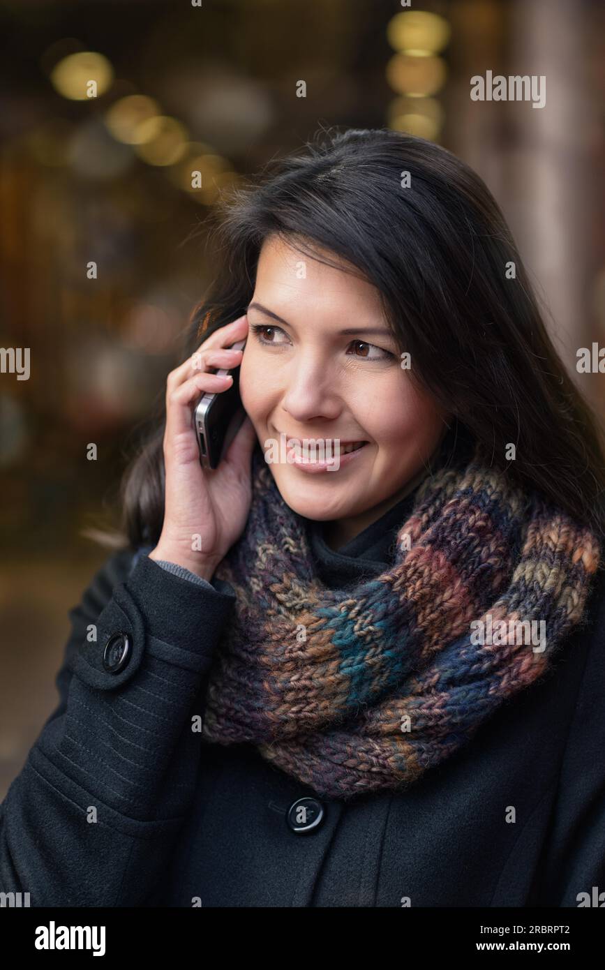 Lächelnde junge Frau im Herbst Mode telefonieren während des Gehens in der Stadt Stockfoto