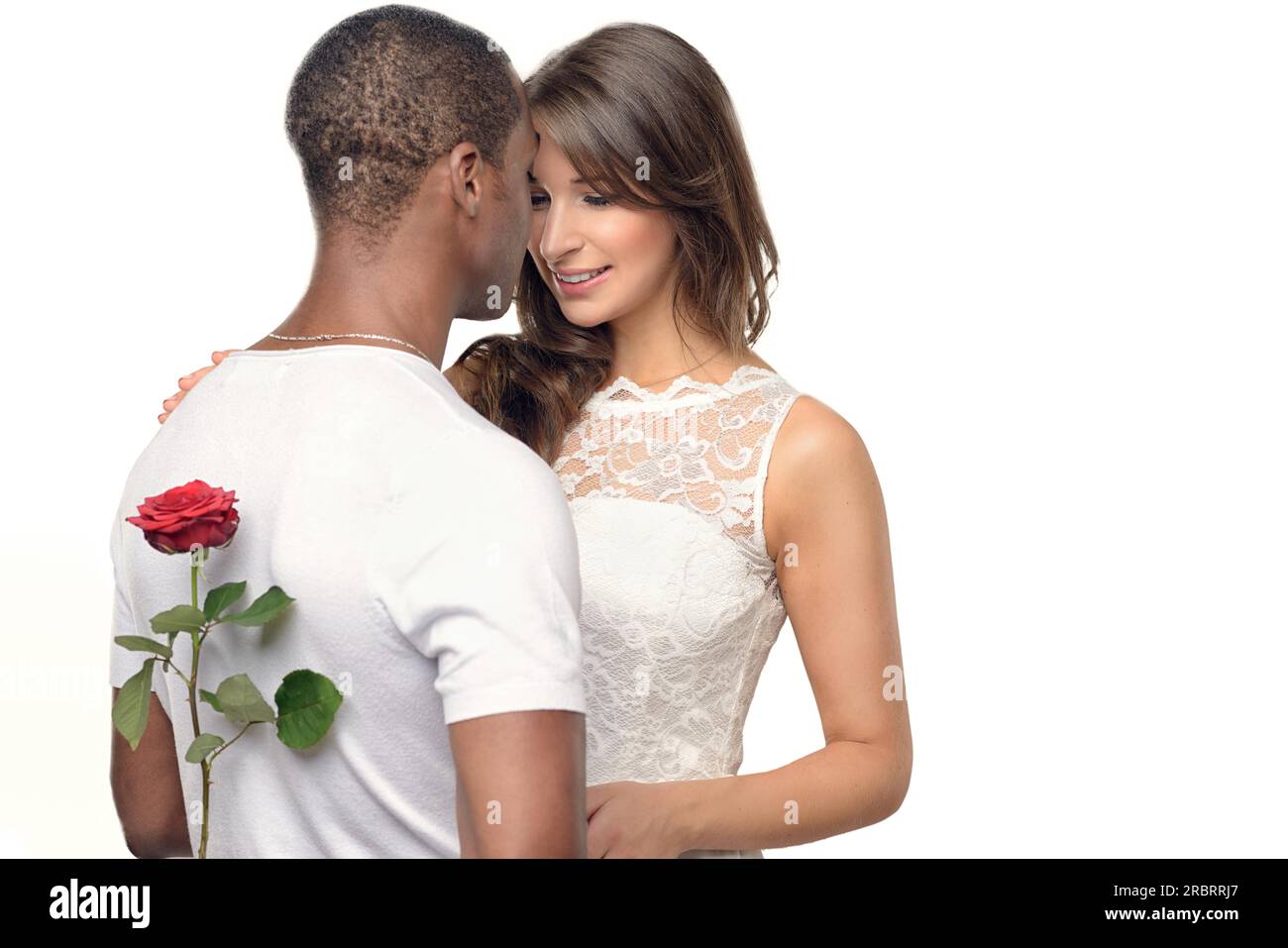 Romantischer junger Mann mit einer hübschen Frau, die hinter seinem Rücken eine rote Rose versteckt, während er sich darauf vorbereitet, sie am Valentinstag oder mit einem Heiratsantrag zu überraschen Stockfoto