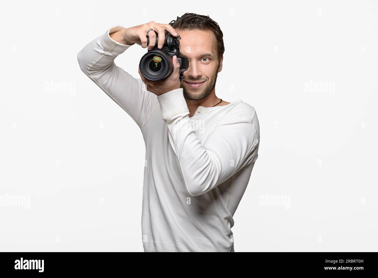 Männlicher Fotograf fokussiert und erstellt ein Bild mit seiner professionellen digitalen DSLR-Kamera, die das Objektiv direkt auf den Betrachter, den Oberkörper richtet Stockfoto