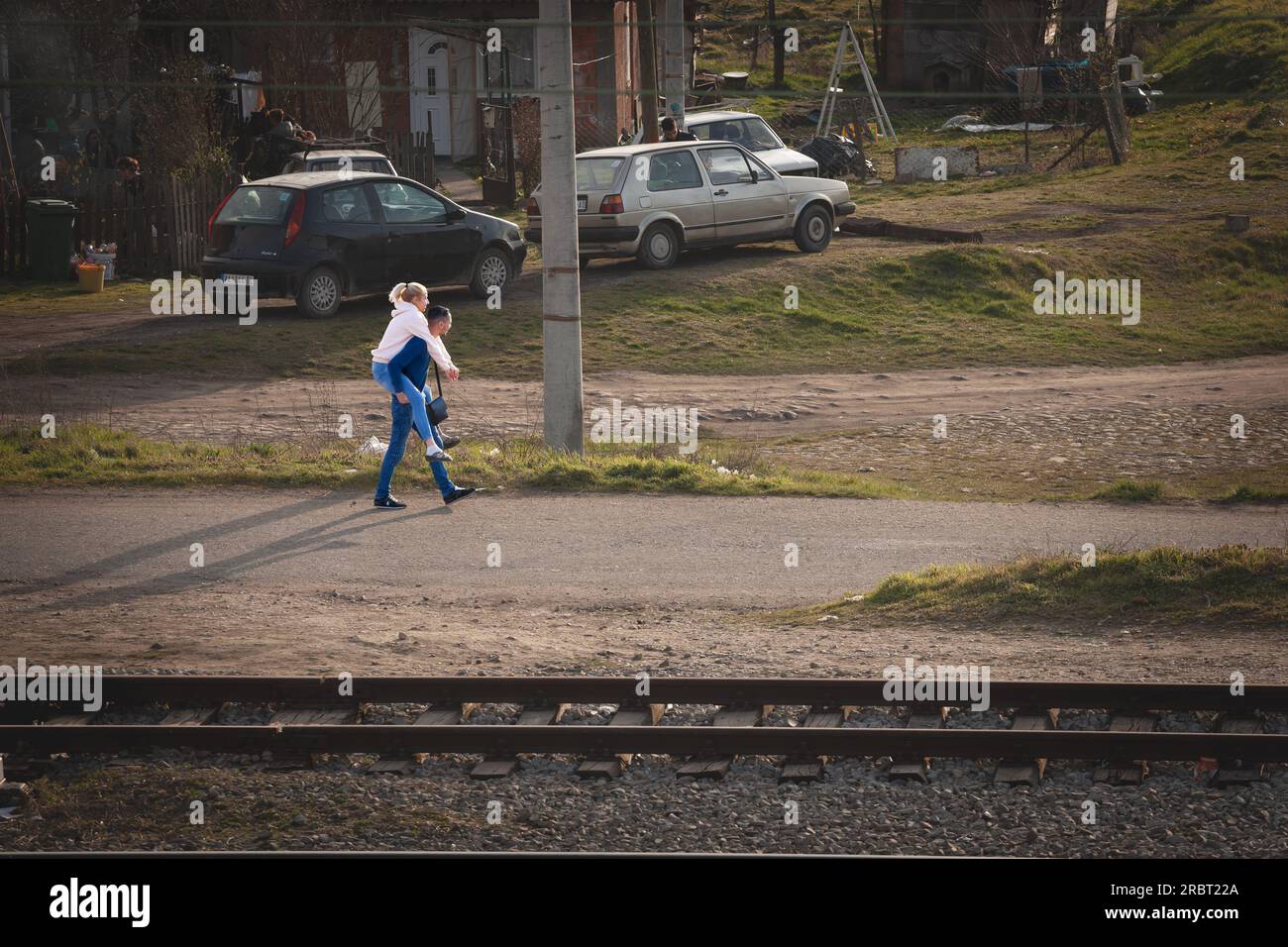 Bild eines Paares, Mann und Frau, jung, serben, die durch die Straßen von Mladenovac, Serbien, laufen, das Mädchen, das auf dem Rücken des Mannes gehoben wird. Stockfoto