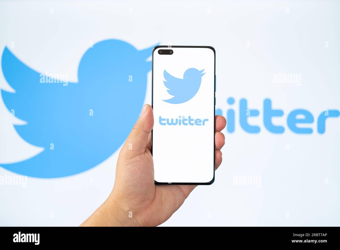 ZHONGSHAN China-Juli 11,2023: Hand hält ein Handy mit Twitter-Logo, ein verschwommener Twitter-Hintergrund auf der Rückseite. Stockfoto