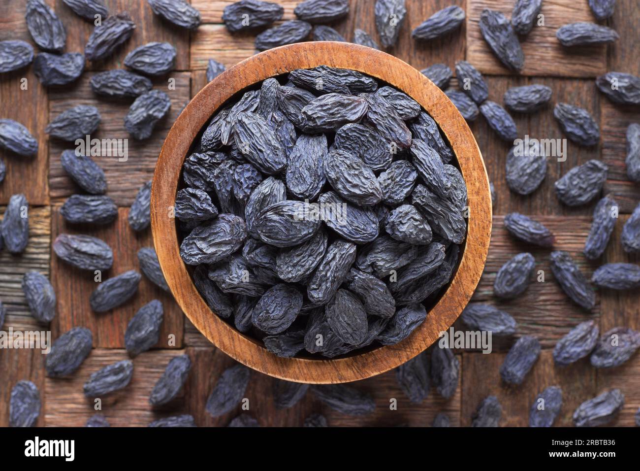 Blaue Rosinen, getrocknete Weintrauben in Schüssel auf Holztischhintergrund. Stockfoto