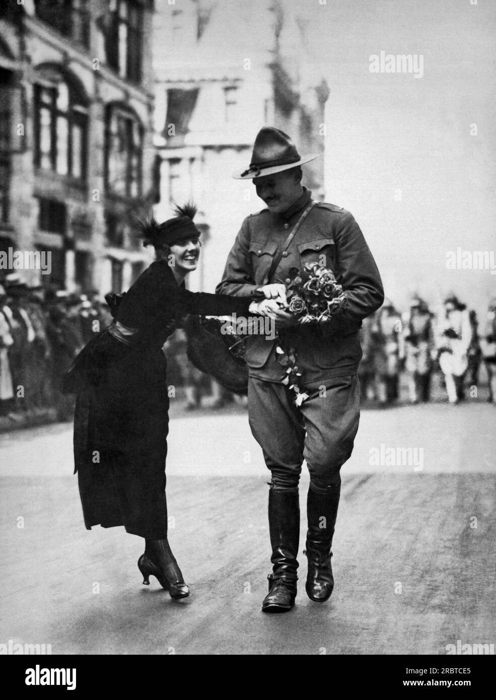 New York, New York: 7. August 1919 Eine junge Frau, die einem zurückkehrenden Soldaten aus dem 1. Weltkrieg bei der Welcome Home Parade einen Blumenstrauß Schenkte Stockfoto