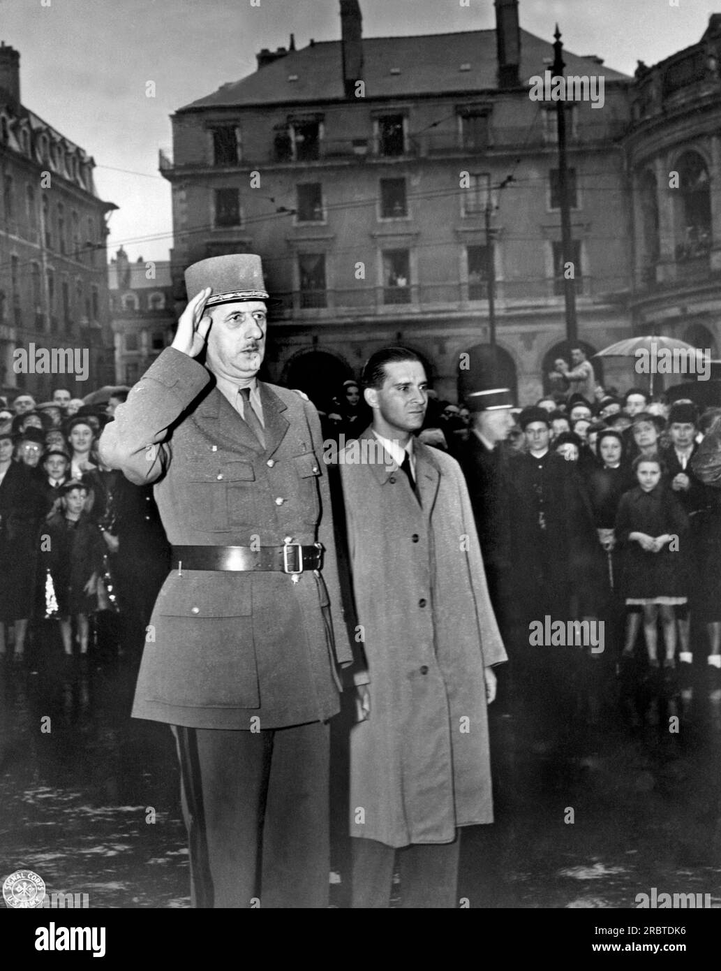 Rennes, Frankreich: 21. August 1944. General Charles de Gaulle grüßt auf dem Stadtplatz von Rennes, Frankreich, der Hauptstadt der Bretagne, während die französische Nationalhymne gespielt wird. Er sprach mit einer großen Gruppe von Bürgern, die in einem strömenden Regen standen, um ihm zuzuhören. Stockfoto