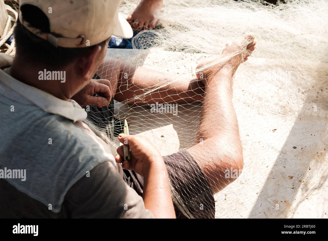 Der Mann repariert ein Fischernetz auf einem Boot in einem Dorf in Indonesien Stockfoto