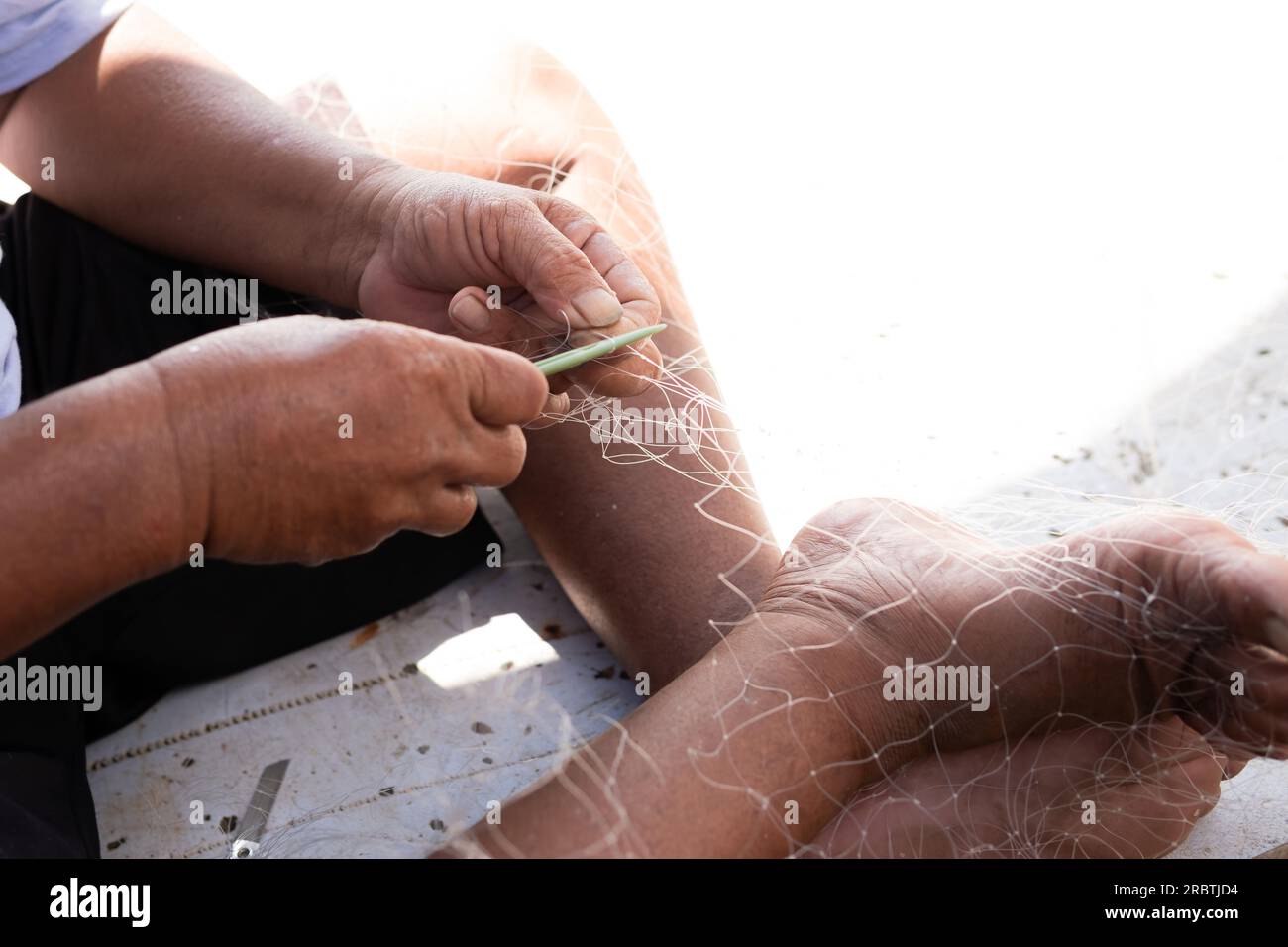Der Mann repariert ein Fischernetz auf einem Boot in einem Dorf in Indonesien Stockfoto