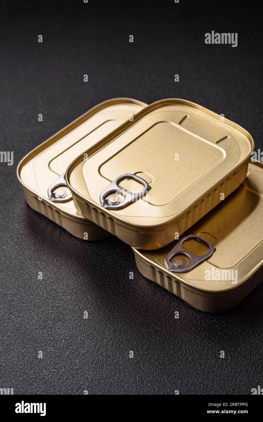 Rechteckige Dose aus Zinn oder Aluminium mit einem Schlüssel auf dunklem Betonhintergrund Stockfoto