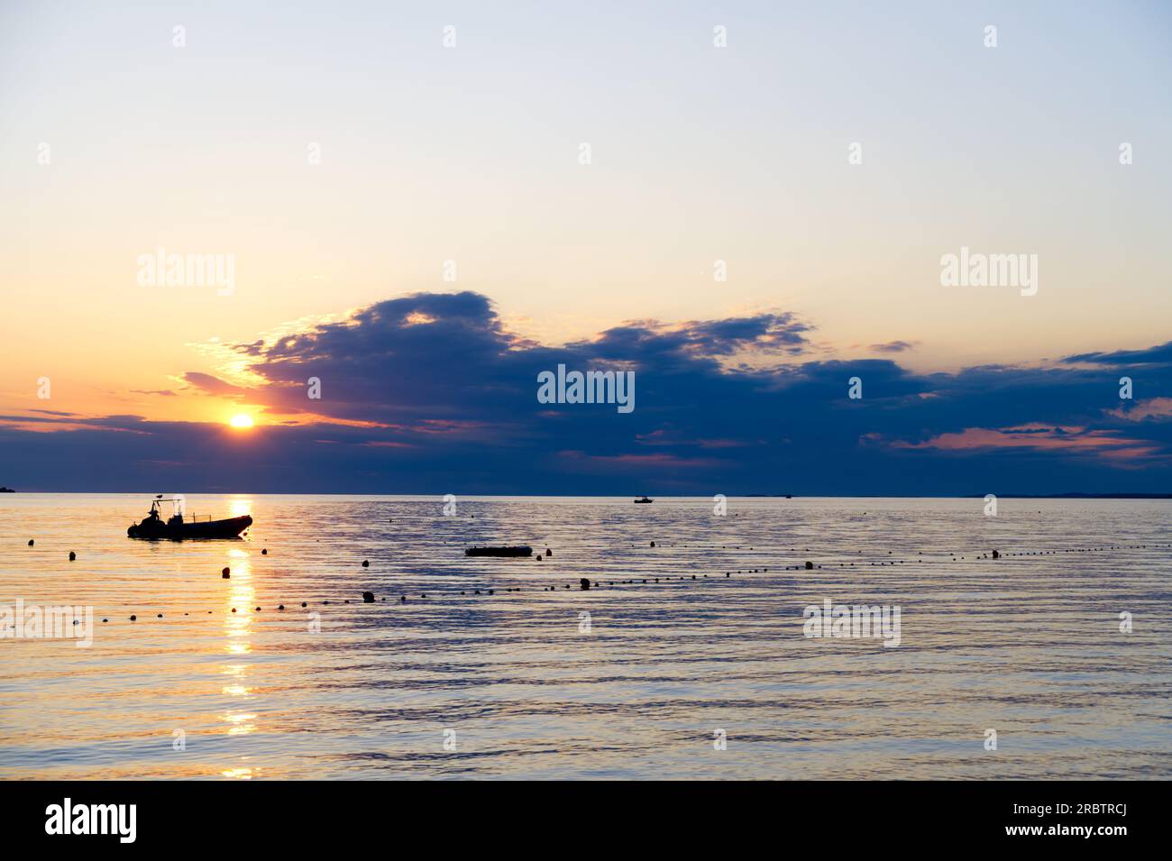Aufblasbares kleines Boot vor Anker bei Sonnenuntergang Ruhe im Meer Entspannungsurlaub Stockfoto