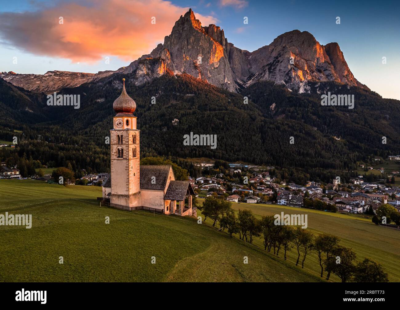 Seis am Schlern, Italien - St. Valentin Kirche und der berühmte Berg Sciliar mit bunten Wolken, blauem Himmel und warmem Sonnenlicht in Südtirol Stockfoto
