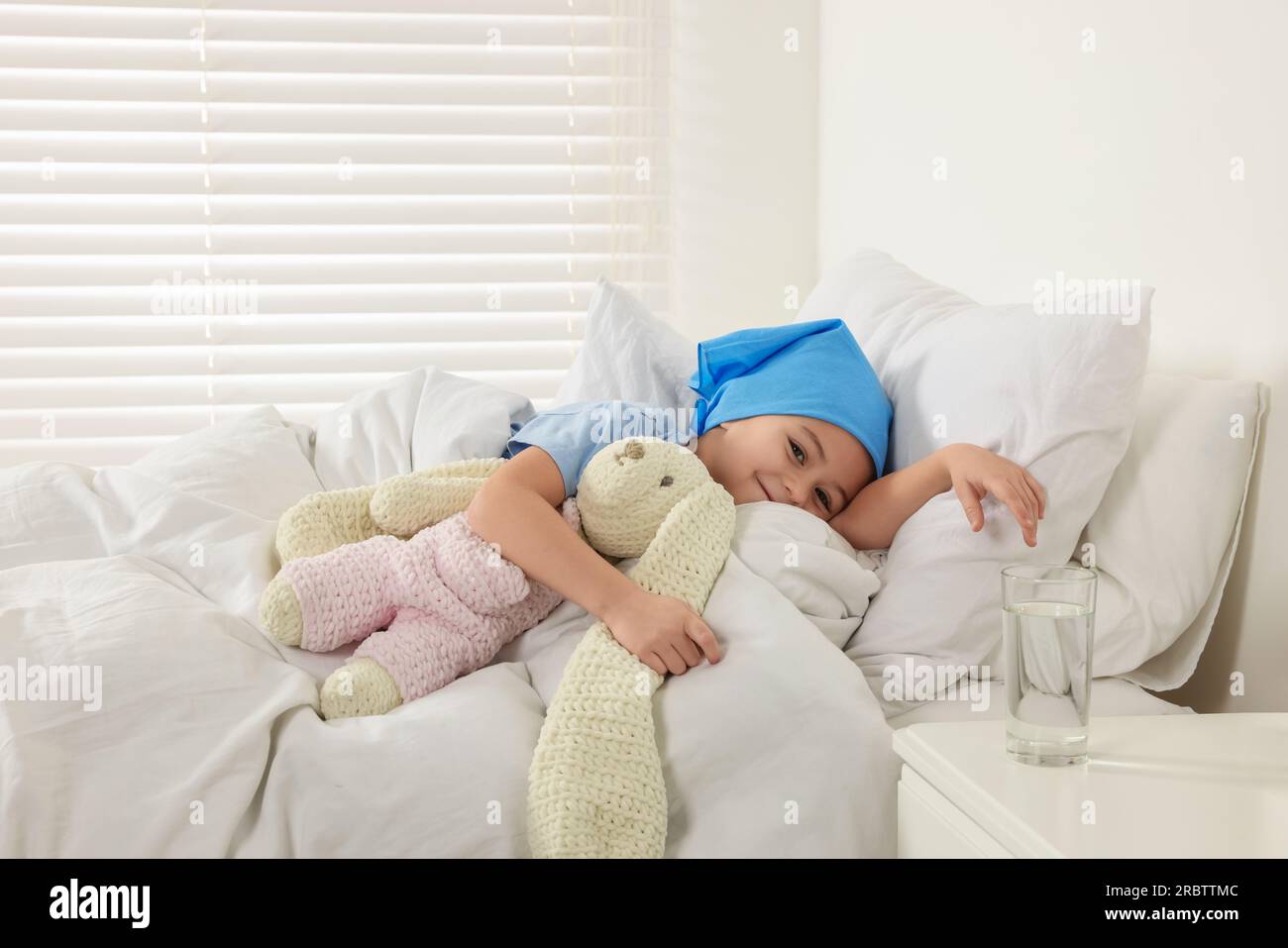 Krebs im Kindesalter. Mädchen, das sich mit dem Spielzeughasen im Krankenhaus ruht Stockfoto