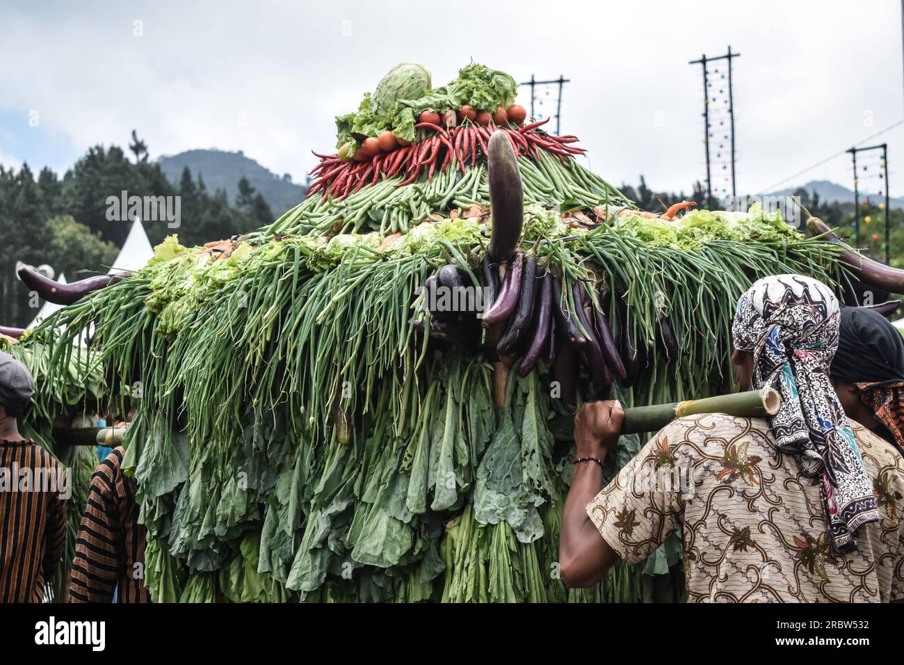 Männer in traditioneller javanesischer Kleidung tragen Berge von Gemüse während des Mount Slamet Festivals Stockfoto