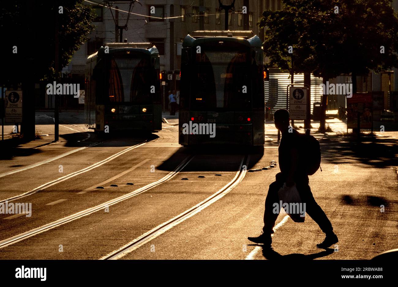 A man crosses the road in front of two subway trains in the city centre of Frankfurt, Germany, early Tuesday, July 11, 2023. (AP Photo/Michael Probst) Stockfoto
