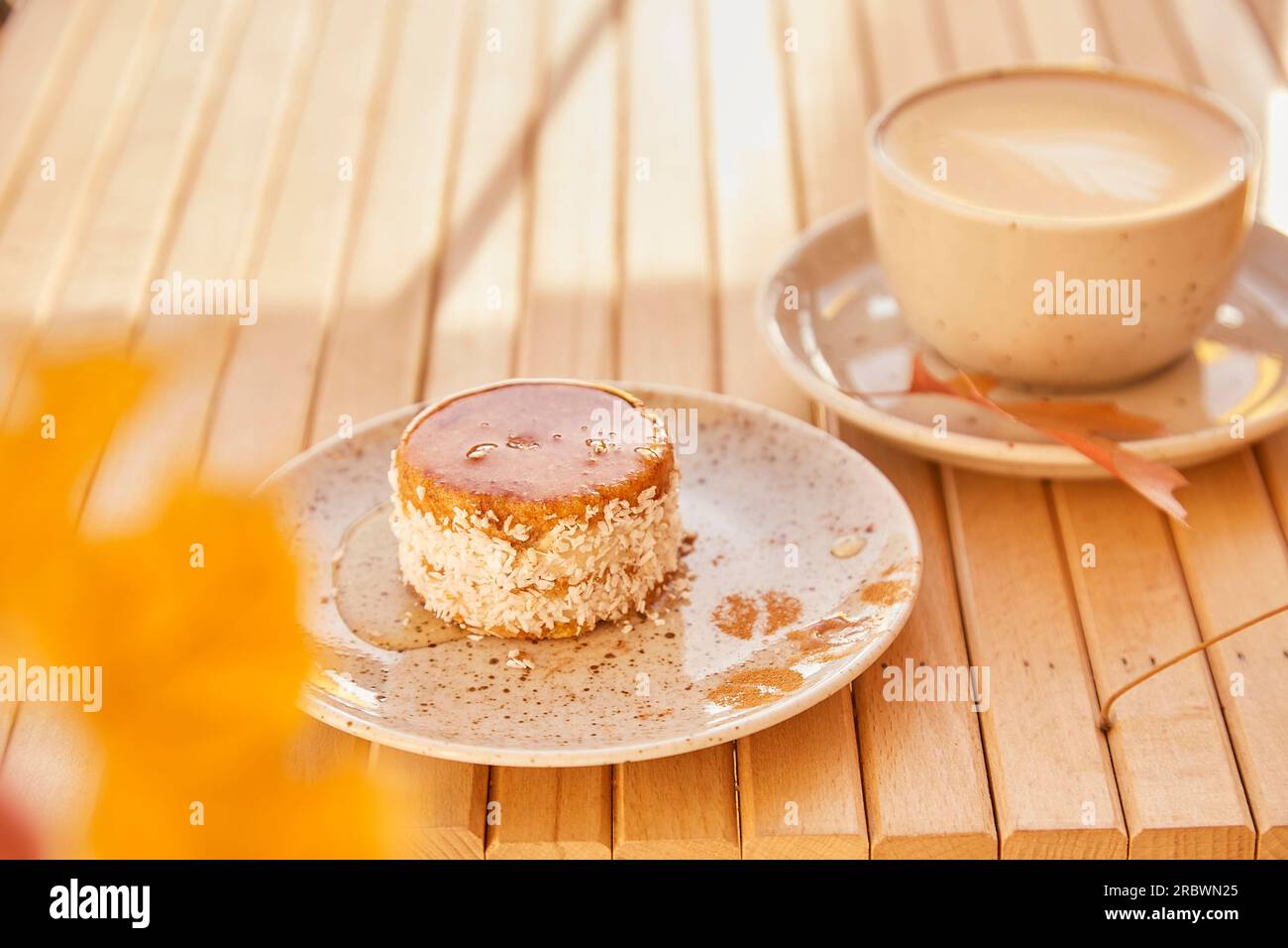 Gesunde Karotten, kein Backen und kein Zucker, leichtes Dessert mit Agavesirup. Glutenfreier Kuchen mit einer Tasse Kaffee draußen im Schatten. Stockfoto