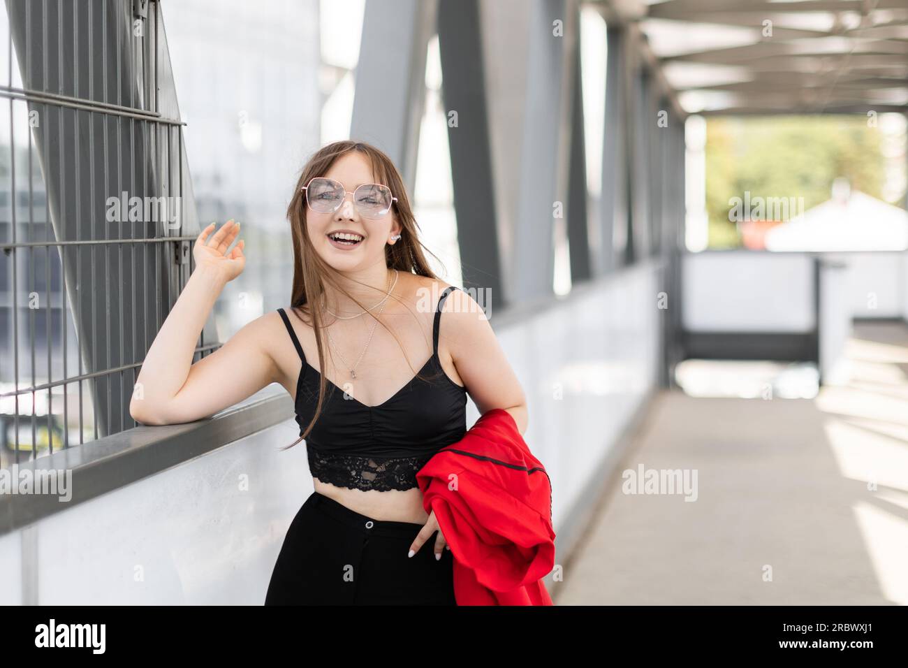 Stilvolle entzückende hübsche Frau mit langen Haaren tragen schwarzen stilvollen Anzug und Sonnenbrille stehen und Spaß auf der Straße. Stockfoto