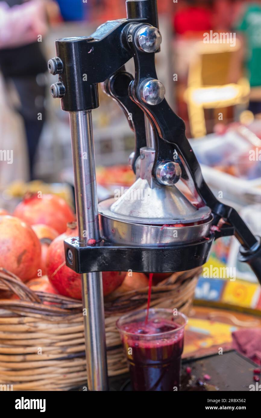 Pressen Sie Saft aus frischen Granatäpfeln mit einer Handpresse auf einem Lebensmittelmarkt Stockfoto