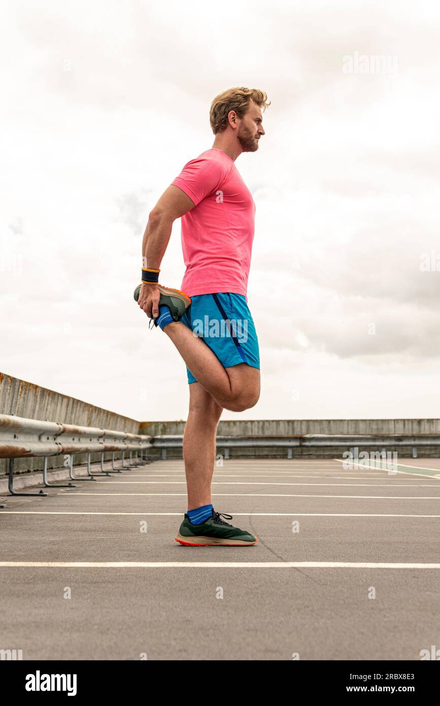 Ein Mann, der vor einem Lauf im Freien sein Bein streckt. Stockfoto