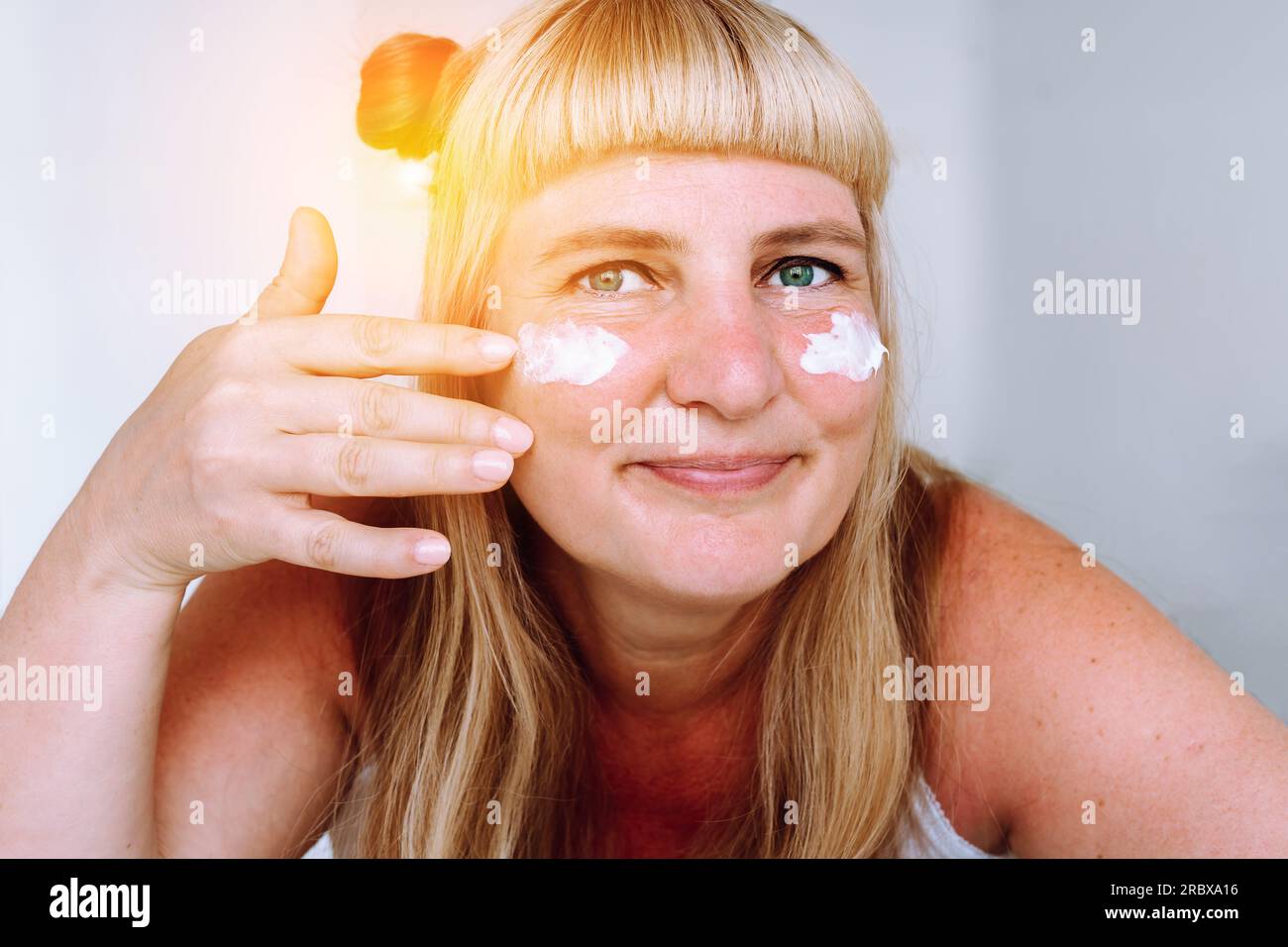 Porträt attraktive blonde Frau mittleren Alters mit kosmetischer Creme Stockfoto