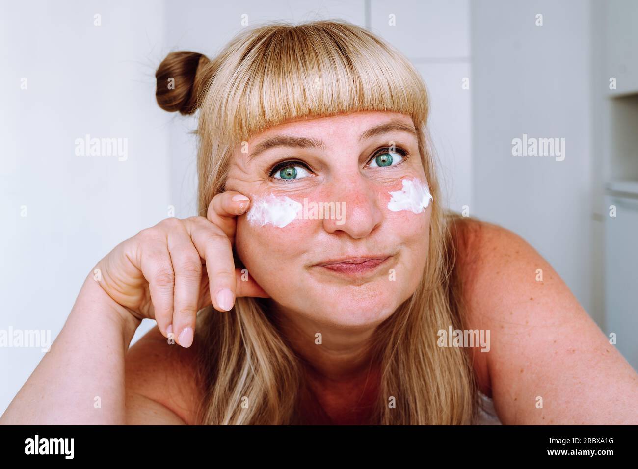 Porträt attraktive blonde Frau mittleren Alters mit kosmetischer Creme Stockfoto
