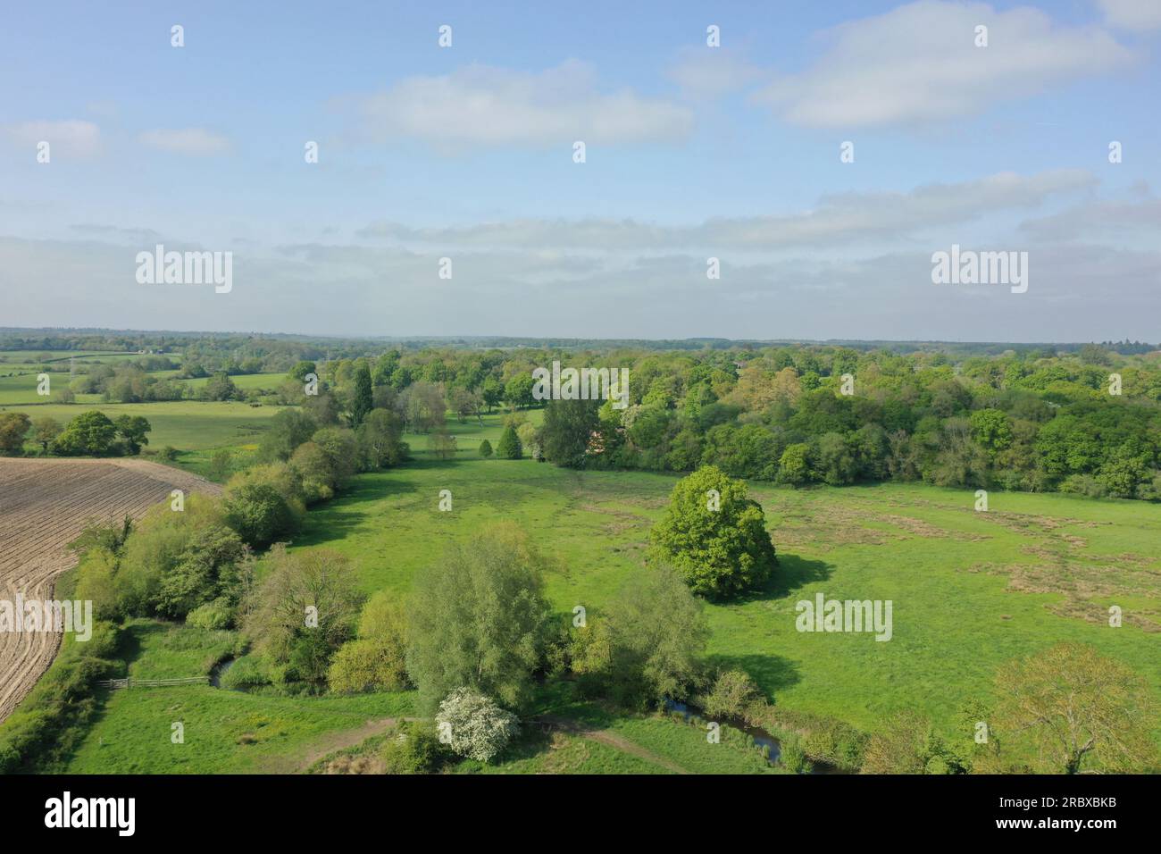 Drohnenperspektive über grünen Feldern von Hook, Hampshire, England. Die Bilder zeigen einen klaren Himmel und grüne Felder, die sich an der Horizontlinie treffen. Stockfoto