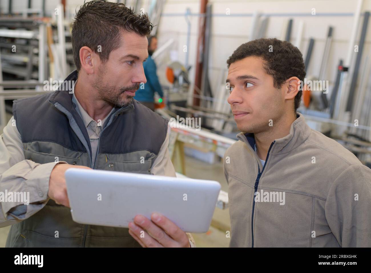 Fabrikarbeiter und Kollege, die in der Fabrik ein digitales Tablet verwenden Stockfoto