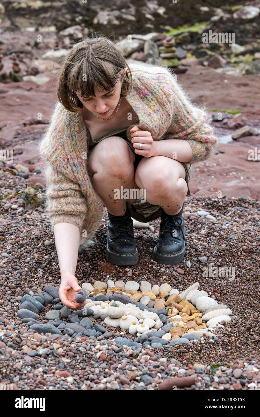 Eine Frau kreiert eine Steinskulptur am Strand, European Land Art Festival, Dunbar, East Lothian, Schottland, Großbritannien Stockfoto