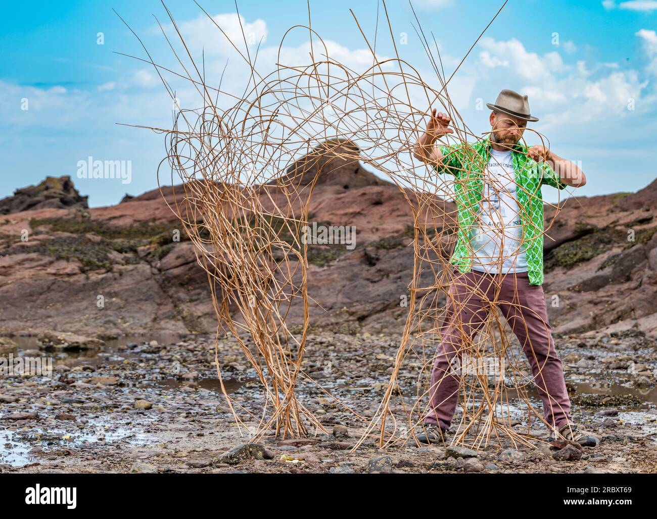 Weaver Mark Antony Haden Ford webt eine Weidenskulptur am Strand, European Land Art Festival, Dunbar, East Lothian, Schottland, Großbritannien Stockfoto