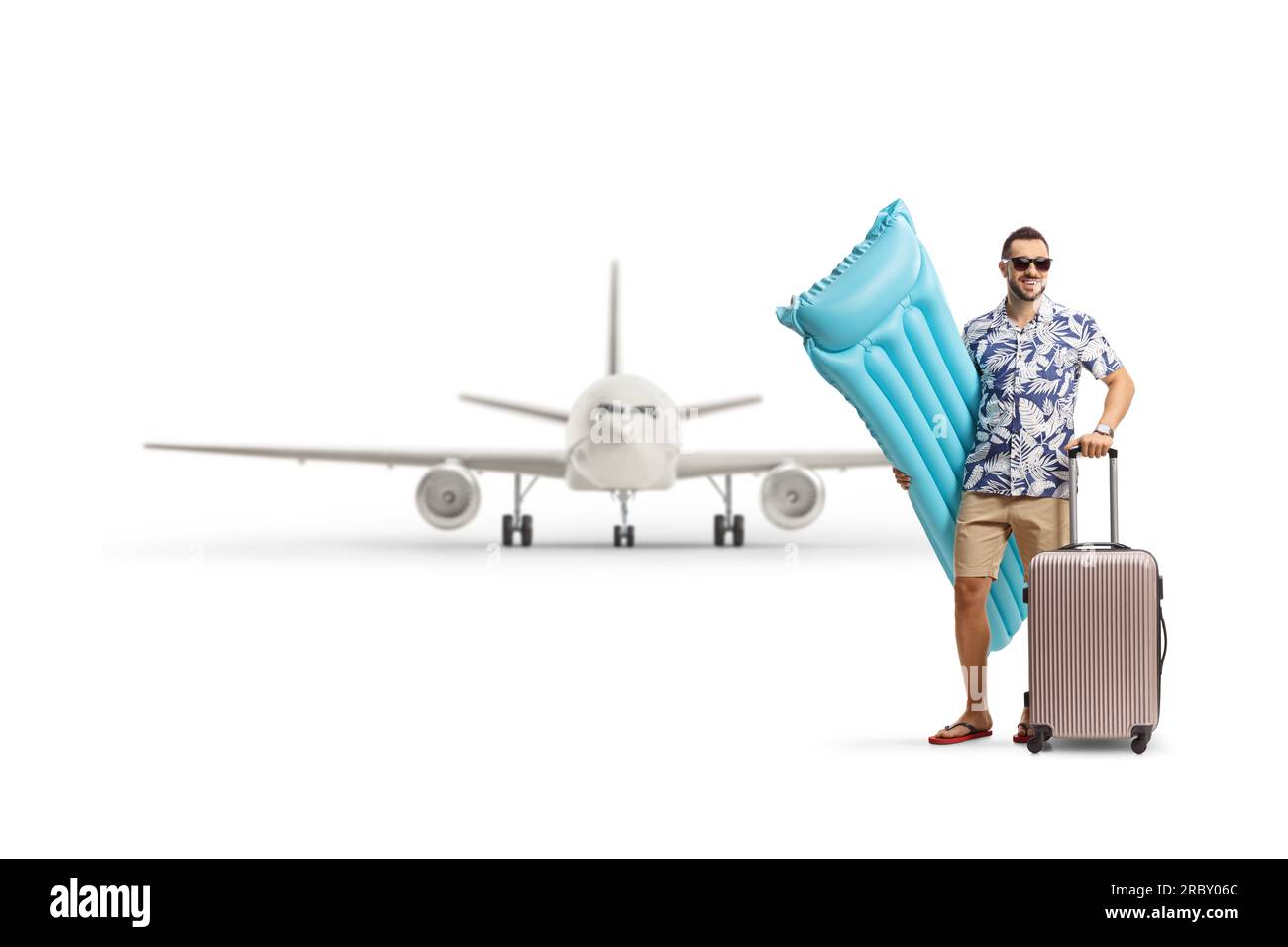 Das Porträt eines Mannes, der eine aufblasbare Matratze und einen Koffer vor einem Flugzeug hält, isoliert auf weißem Hintergrund Stockfoto