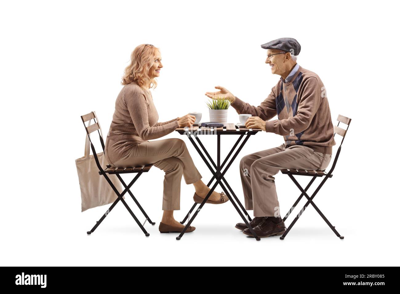 Ein älterer Mann sitzt an einem Tisch und trinkt eine Tasse Kaffee mit einer Frau isoliert auf weißem Hintergrund Stockfoto
