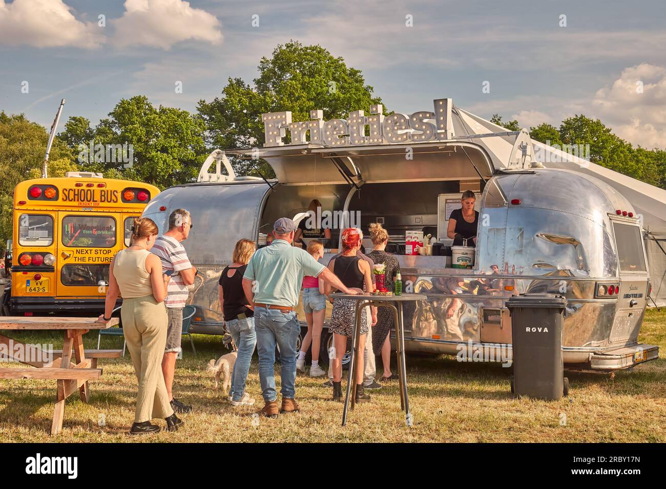 Aalten, Niederlande - 23. Juni 2023: Klassischer Food-Truck-Wohnwagen, der Kartoffelpommes frites verkauft, während Leute auf einer Landmesse in Aalten bestellen Stockfoto