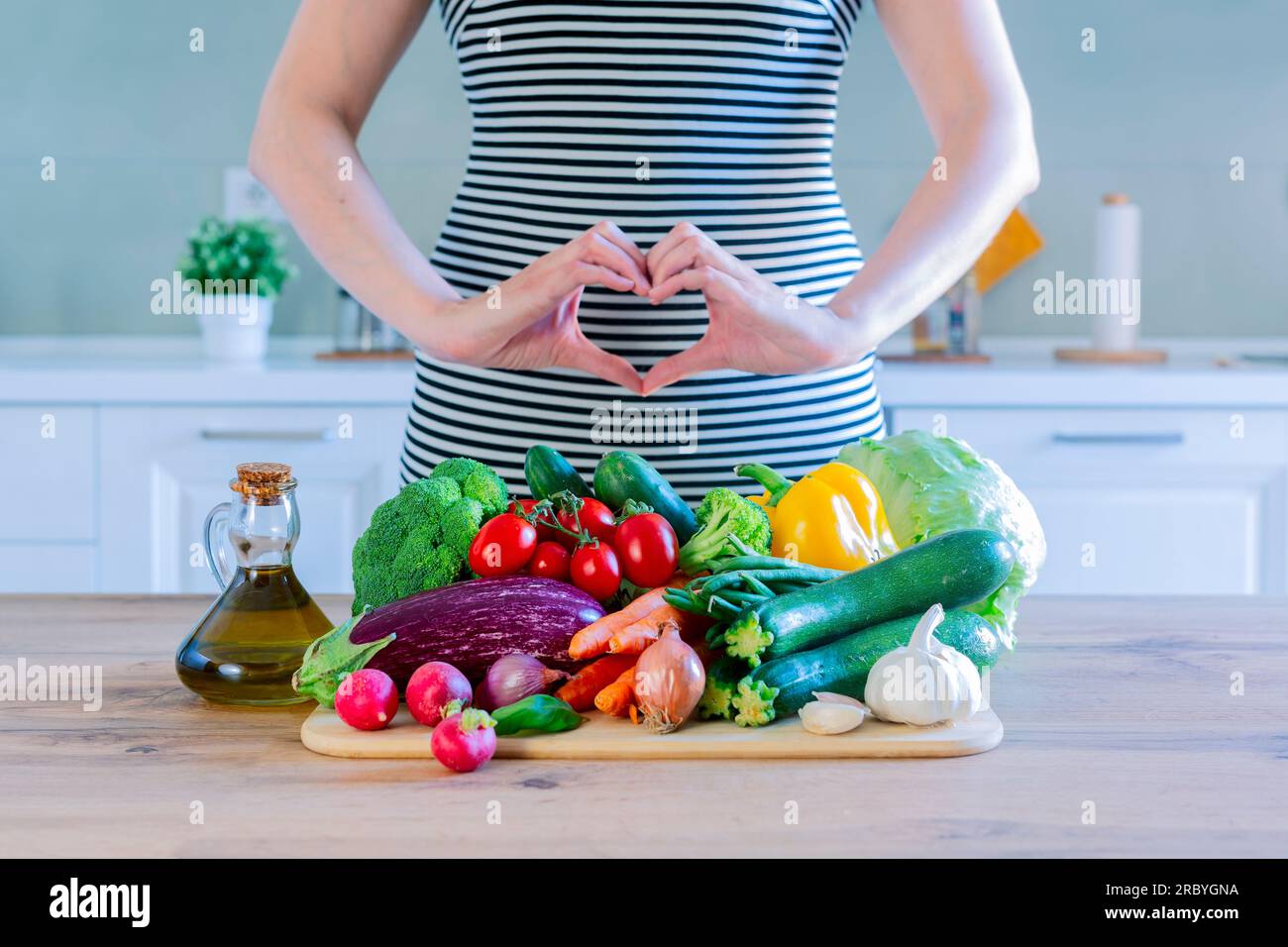 Frisches Gemüse auf einem Holztisch mit Frau, die Liebesherz mit ihren Händen macht - gesunde Ernährung Lifestyle Konzept für Vegetarier oder Diät Gewichtsverlust ACTI Stockfoto