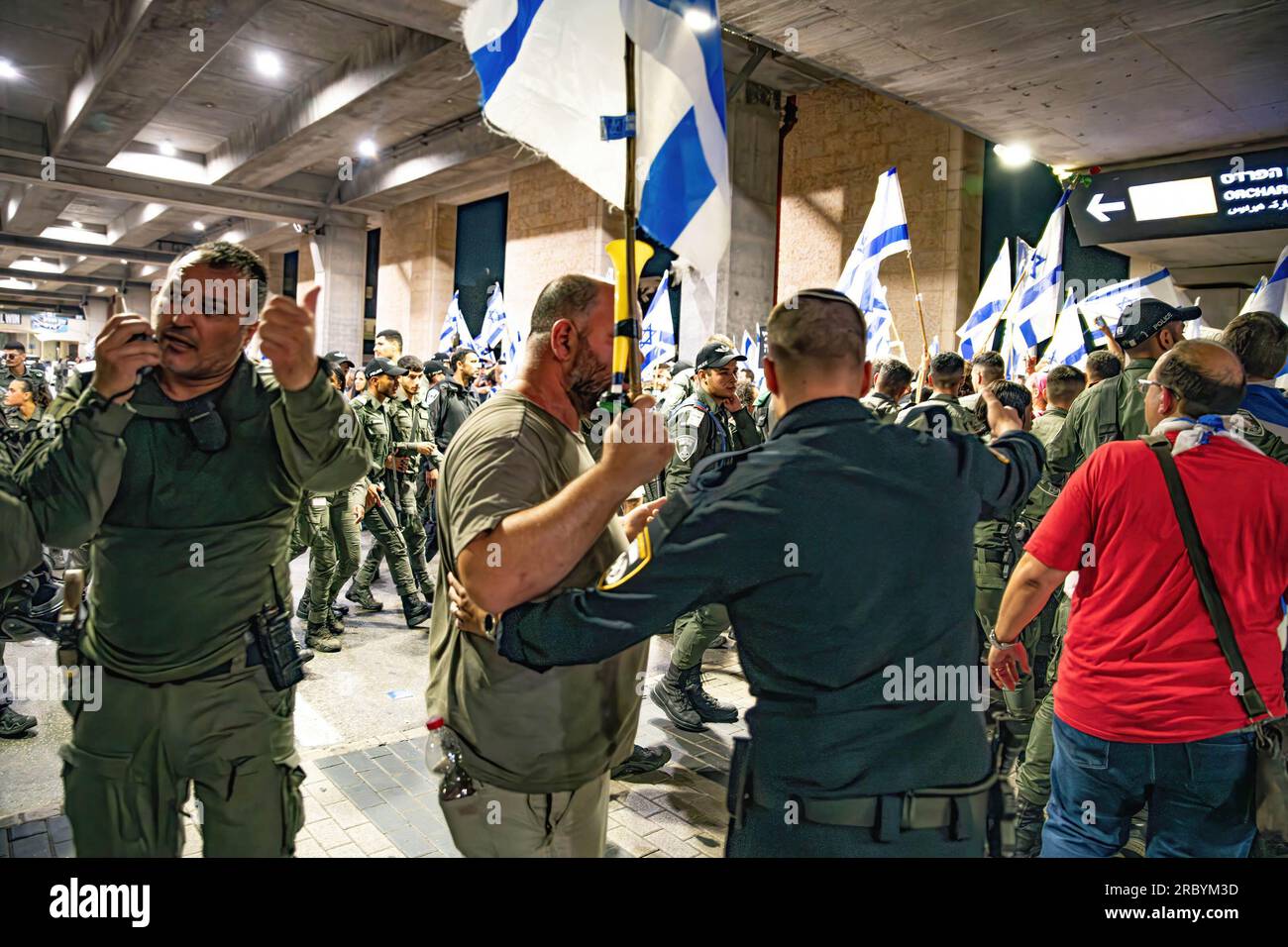 Ein israelischer Grenzpolizeisoldat sah, wie er während einer Demonstration gegen die Justizreform am Flughafen Ben Gurion einen Demonstranten drängte. Stockfoto