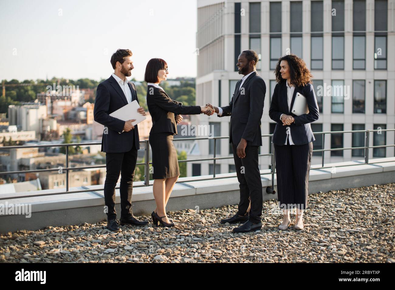 Birassische Geschäftspartner geben sich die Hand, um die Vereinbarung gegenseitiger Investitionen in Neubauten zu bestätigen. Vier Unternehmer in Anzügen treffen sich im Büro Stockfoto