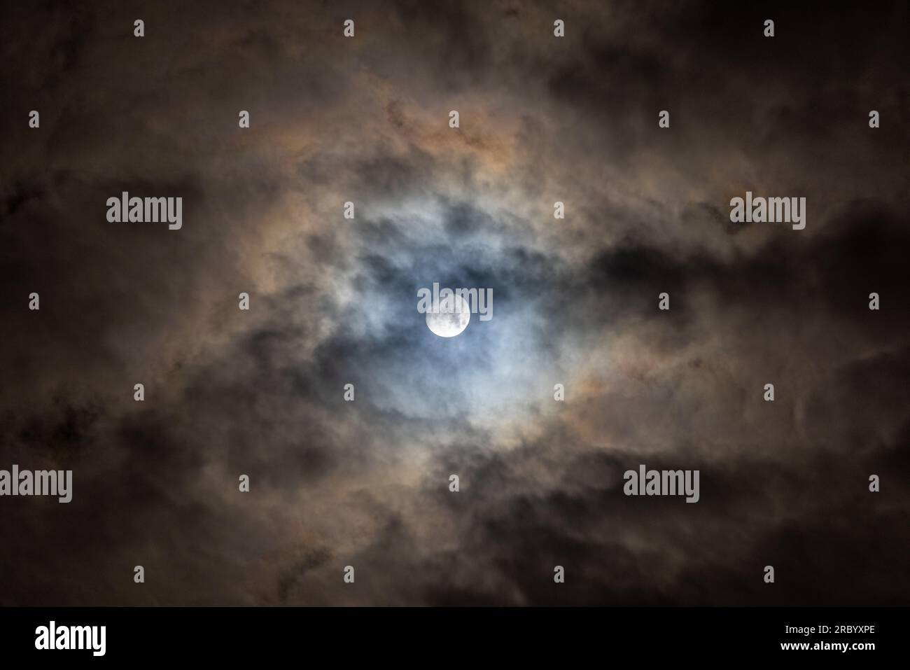 Vollmond, der durch dünne Wolken scheint, führt zu bunten Mustern Stockfoto