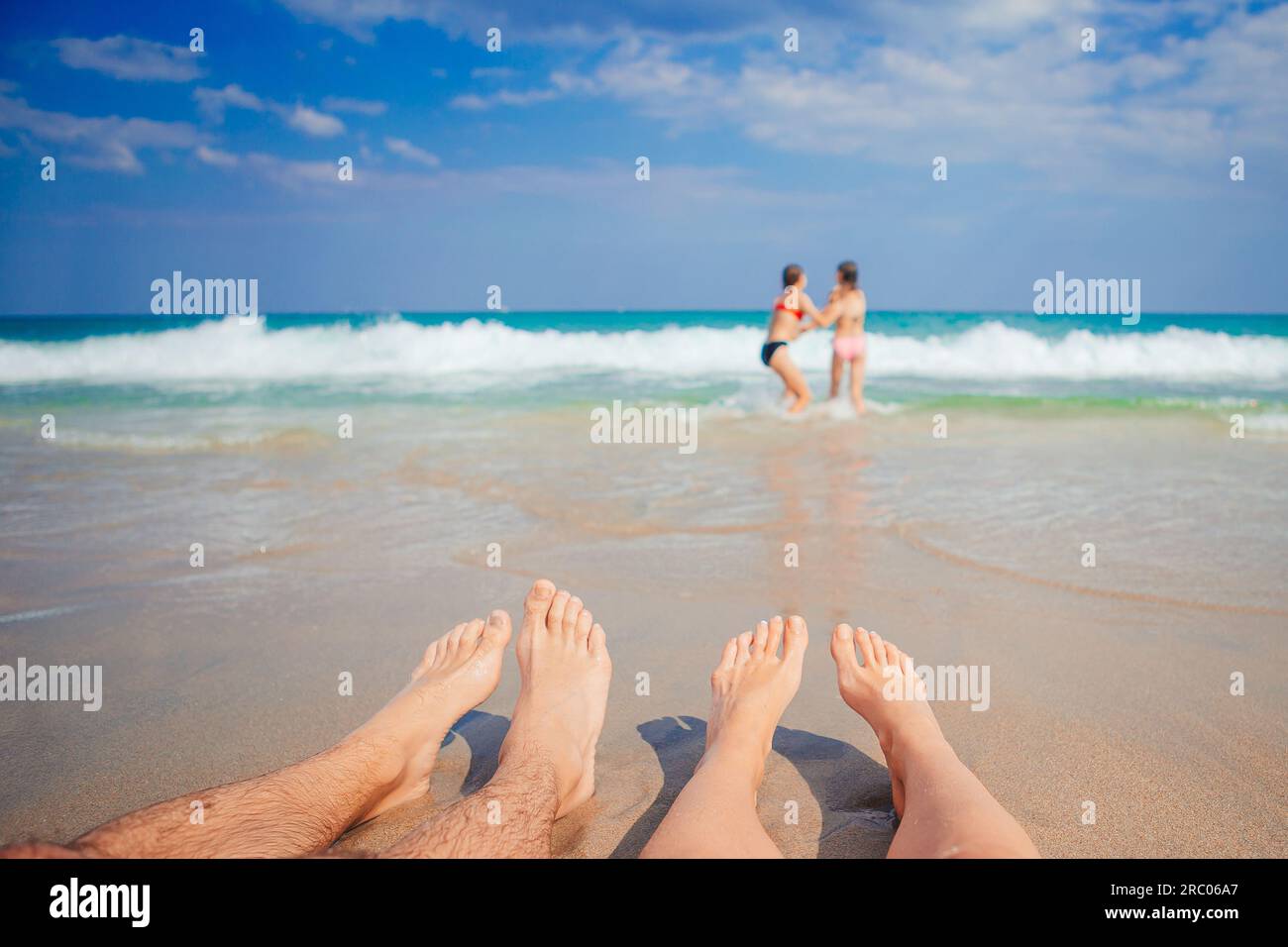 Nahaufnahme der Füße der Familie am weißen Sandstrand. Kinder spielen im Sommerurlaub am Strand im seichten Wasser. Hochwertiges Foto Stockfoto