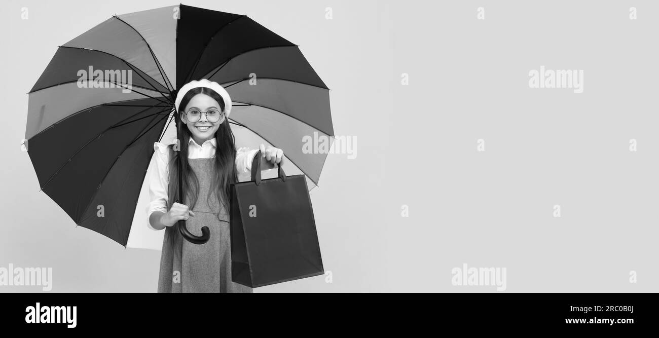 Happy teen Mädchen unter bunten Regenschirm im Herbst Saison halten Einkaufstasche, Herbst einkaufen. Kind mit Herbstschirm, regnerisches Wetter, horizontal Stockfoto