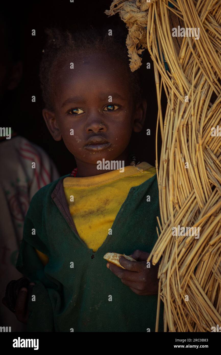 Ein herzzerreißendes Porträt fängt den düsteren Blick des tschadischen Jungen ein, verkleidet in verwitterter Kleidung, mit einer Mandarinenabteilung Stockfoto