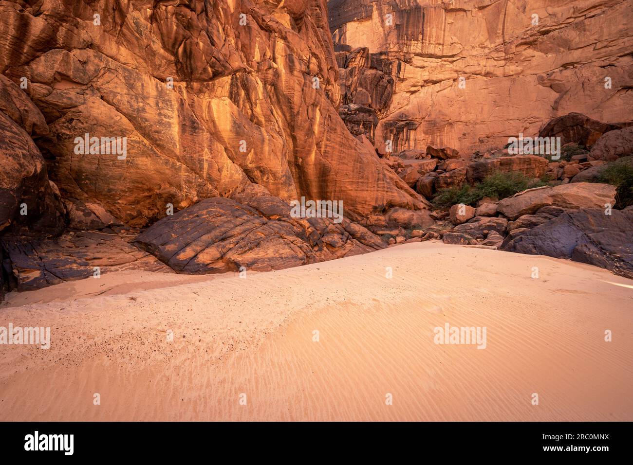 Eingebettet in die Schönheit der Wüste, bilden die orangefarbenen Sandsteinwände und fesselnden Felsenabstracts eine faszinierende Landschaft in Guelta d'Archei Stockfoto