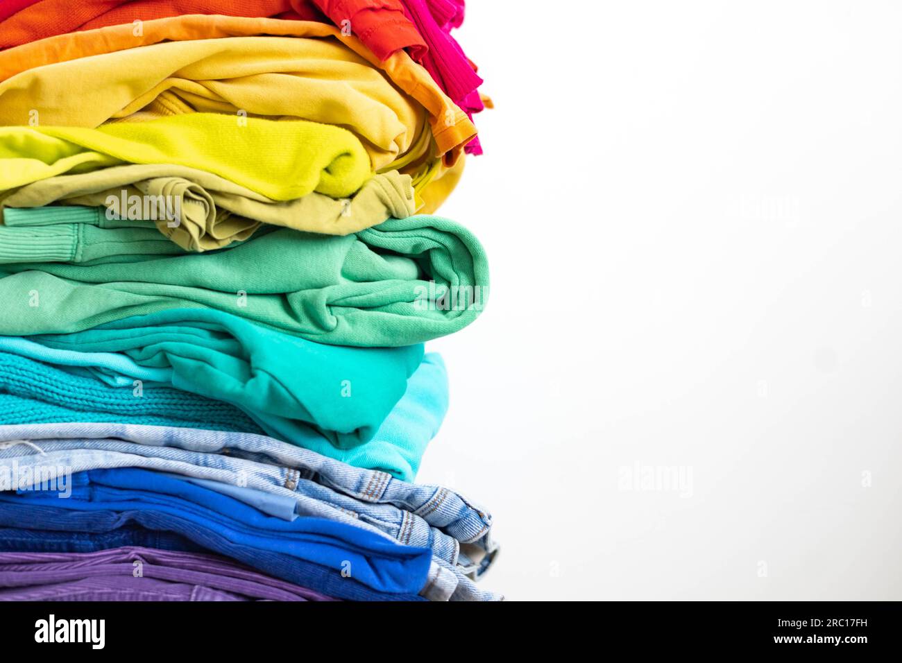 Ein Stapel Kleidung in verschiedenen Farben. Der Begriff des bewussten Bekleidungskonsums. Stockfoto